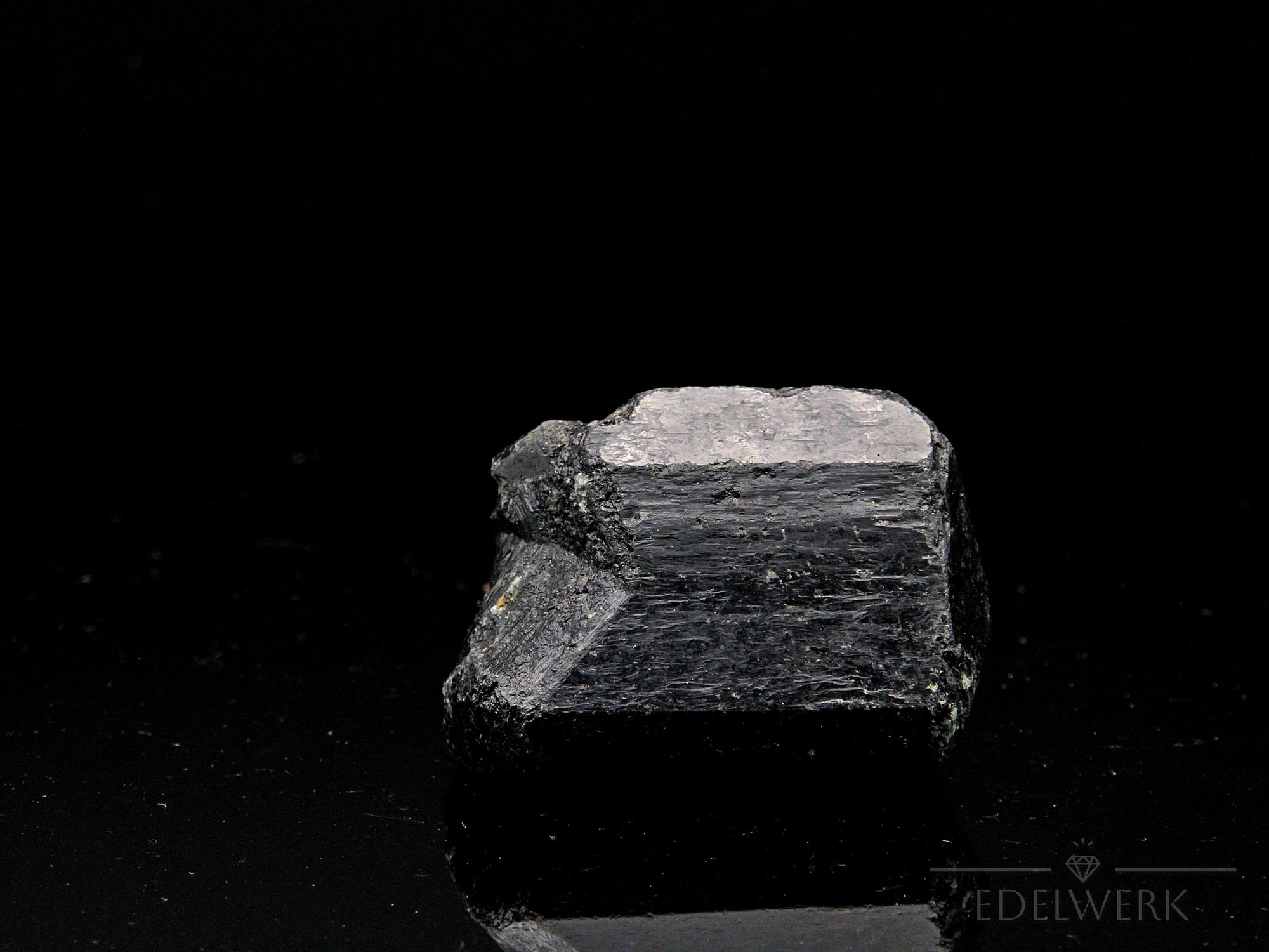 Schwarzer Turmalin, fördert schützende Energie, glänzende schwarze Oberfläche.